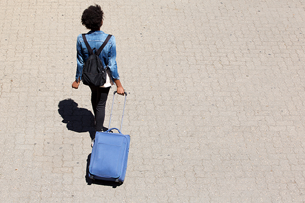 Top view portrait of young afro american woman walking on the street with luggage